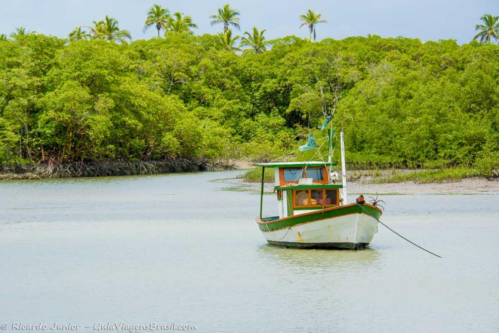 Imagem de um barco ancorado no mar calmo da Praia Corumbau.